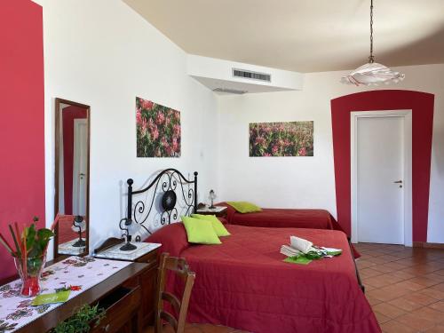 a bedroom with two beds with red sheets and a table at Azienda Agrituristica Bergi in Castelbuono
