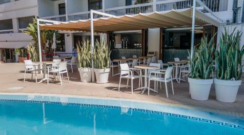 a restaurant with tables and chairs next to a pool at Ona Palm Beach in Playa de las Americas