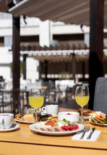 a table with plates of food and glasses of wine at Ona Palm Beach in Playa de las Americas