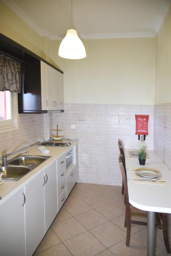 a kitchen with a sink and a table with chairs at Spyridoula Resort in Corfu in Gouvia