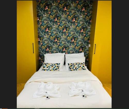 - un lit avec des draps et des oreillers blancs et un mur fleuri dans l'établissement Appartement Paris 11 - 2 chambres - 2 sdd - 2 wc, à Paris