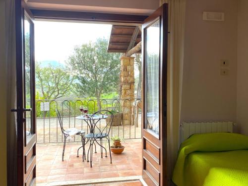 a bedroom with a balcony with a table and chairs at Azienda Agrituristica Bergi in Castelbuono