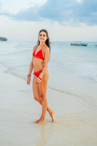 a woman in a red bikini standing on the beach at Hekaya Zanzibar in Pingwe