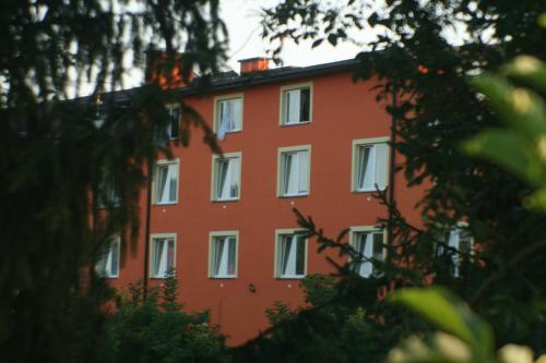 a red building with white windows and trees at Daisy Superior in Kraków