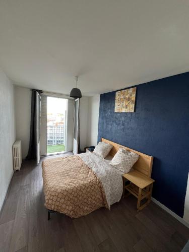 une chambre avec un lit et un mur bleu dans l'établissement Chambre chez Bryan, à Toulouse
