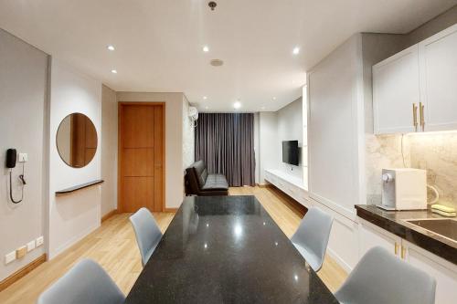a kitchen and dining room with a black table and chairs at Brand New and Nice 2BR Apartment at The Reiz Condominium Medan By Travelio in Medan