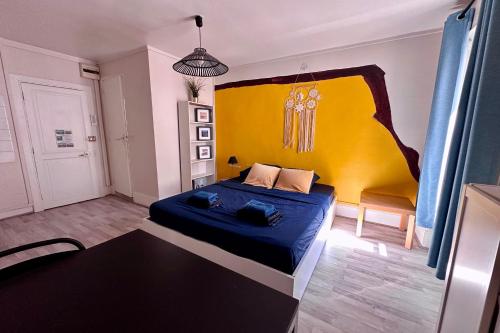 - une chambre avec un lit bleu et une tête de lit jaune dans l'établissement Charming Duplex in the Heart of Fontainebleau, à Fontainebleau