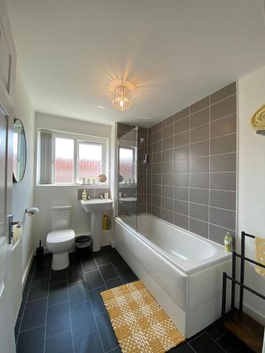 a bathroom with a tub and a toilet and a sink at Apollo Apartment in Coventry