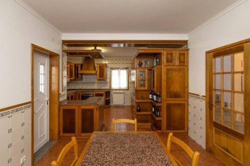 a kitchen with wooden cabinets and a table in a room at Vivenda Senhora das Areias in Aveiro