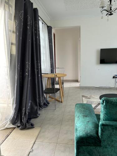 a living room with black curtains and a green couch at Teakwood in Eldoret