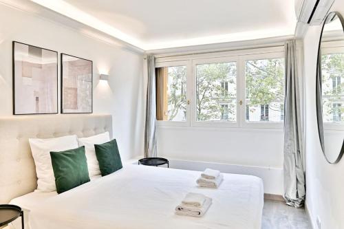 une chambre blanche avec un lit et une fenêtre dans l'établissement Appartement ensoleillé proche Buttes Chaumont, à Paris