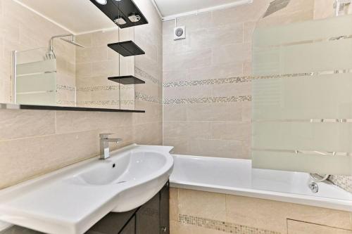 une salle de bain avec un lavabo, une baignoire et un miroir dans l'établissement Appartement ensoleillé proche Buttes Chaumont, à Paris