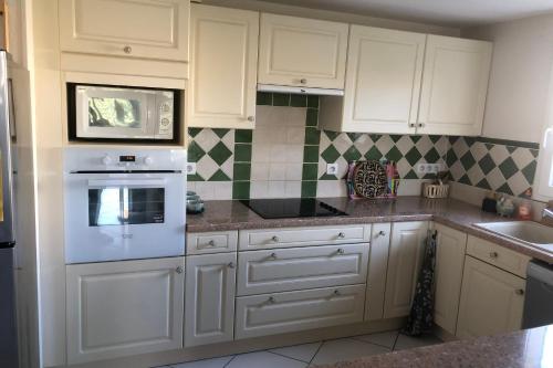 une cuisine avec des armoires blanches et un four à plaques de cuisson dans l'établissement House with garden and terrace near beach, à Port-la-Nouvelle