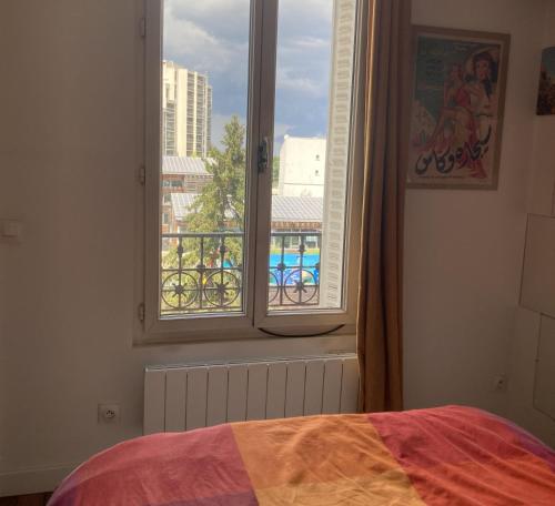 une chambre avec une fenêtre avec vue sur une ville dans l'établissement Cosy flat near the Canal and Paris, à Pantin