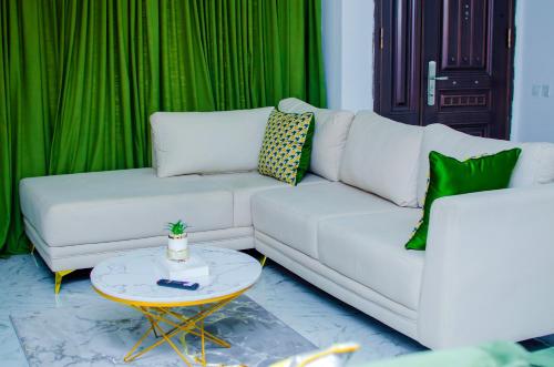 a living room with a white couch and green curtains at Tranquil Old Bodija Retreat - 3 Bedroom House in Ibadan