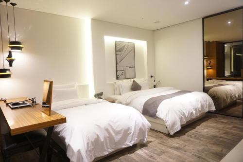 a bedroom with two beds and a desk and a mirror at Ischia Hotel in Yongin