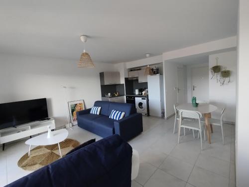 un salon avec un canapé bleu et une table dans l'établissement Appartement Spacieux et Lumineux, à Cogolin