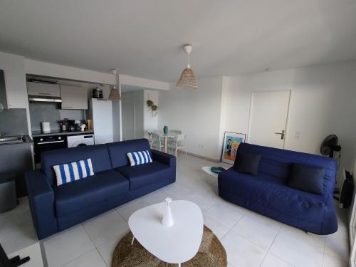 un salon avec deux canapés bleus et une table dans l'établissement Appartement Spacieux et Lumineux, à Cogolin