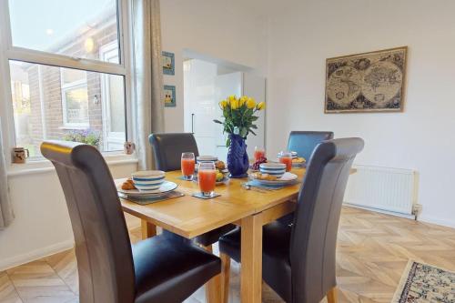 a dining room table with chairs and a vase of flowers at Bright & Spacious 4 Bed Victorian Home by Blue Buzzard Property in Kent