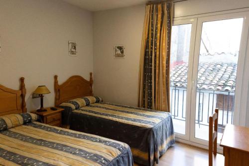 a bedroom with two beds and a window with a balcony at Pensión El Gallo in Olvega