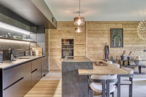 une cuisine avec un grand îlot et des tabourets de bar dans l'établissement Charmant Appartement au Cœur de Megève avec Jardin privatif, à Megève