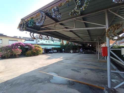 an empty parking lot with awning and flowers at KT Knight Hotel in Surin