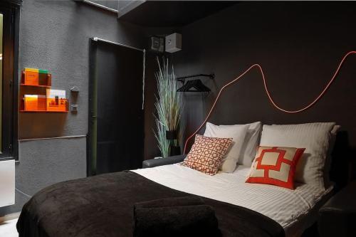 - une chambre dotée d'un grand lit avec des oreillers rouges et oranges dans l'établissement Le Dark, à Paris