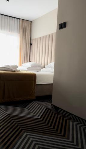 a bedroom with a bed and a window and a rug at Hotel Panorama Nowy Sącz in Nowy Sącz