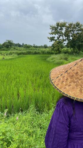 a person wearing a hat sitting in front of a field at Vana The Forest Farm in Saralgaon