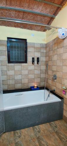 a large bath tub in a room with a window at Vana The Forest Farm in Saralgaon