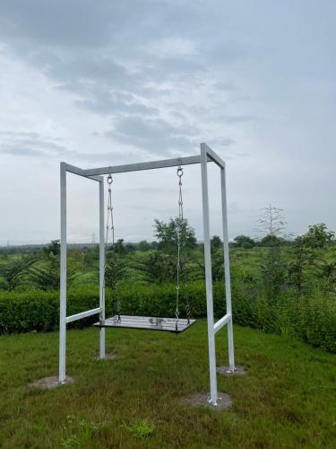 a swing in the middle of a field at Vana The Forest Farm in Saralgaon