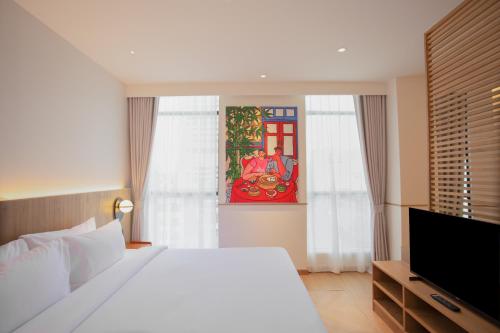 a bedroom with a white bed and a tv at Lub d Bangkok Chinatown - Steps from Sam Yod MRT Station in Bangkok