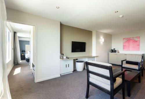 a living room with a television and a table and chairs at Sudima Auckland Airport in Auckland