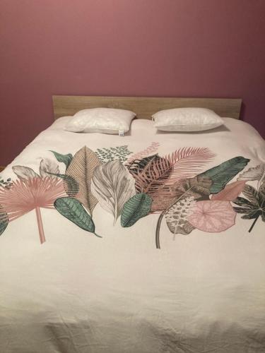 - un lit avec une couverture recouverte de feuilles dans l'établissement Chez nous !, à Luméville-en-Ornois