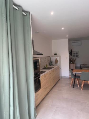 - une cuisine avec des rideaux verts dans une chambre avec une table dans l'établissement Maison de ville - La Sauvetat, à La Sauvetat