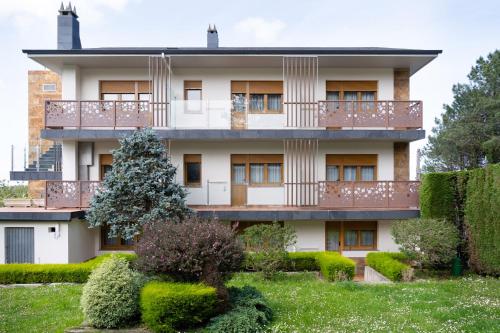 a building with a balcony and some bushes at Hotel el Pinar in Villapedre