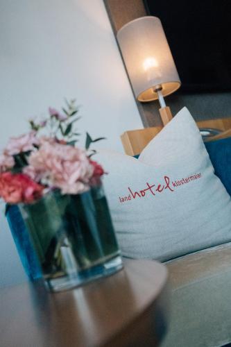a vase of flowers on a table next to a pillow at Klostermaier Hotel & Restaurant in Icking