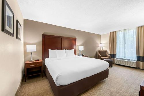 a hotel room with a large bed and a chair at Comfort Inn & Suites Durham near Duke University in Durham