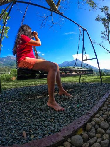 a woman is sitting on a swing at Belihuloya Hideout Villa in Belihul Oya