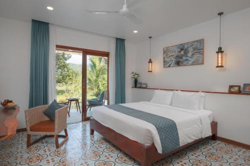 a bedroom with a bed and a chair and a window at La Passion by Achariyak in Koh Rong Sanloem