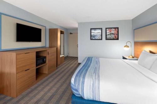 a hotel room with a bed and a flat screen tv at AmericInn by Wyndham North Branch in North Branch