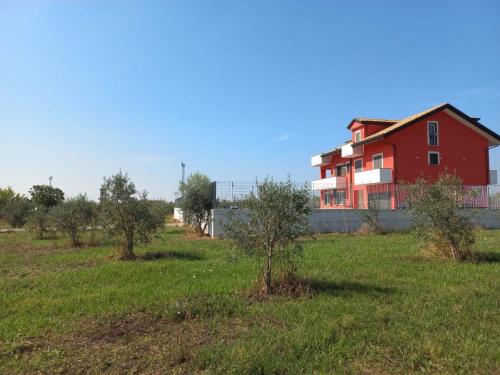 una casa roja en medio de un campo con árboles en Villa degli Ulivi, en Montecorvino Rovella