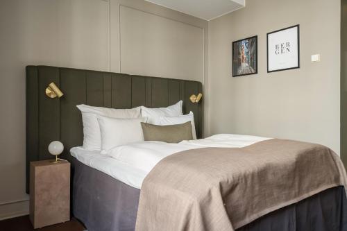a bedroom with a large bed with a gray headboard at Home Hotel Bryggen in Bergen