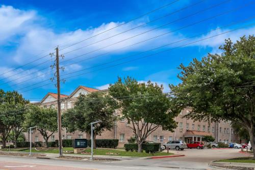 a large building with trees in front of a street at MainStay Suites Addison-Dallas in Addison