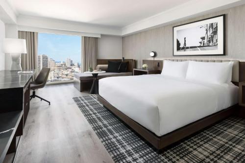 a bedroom with a large white bed and a living room at Hyatt Regency San Francisco Downtown SOMA in San Francisco