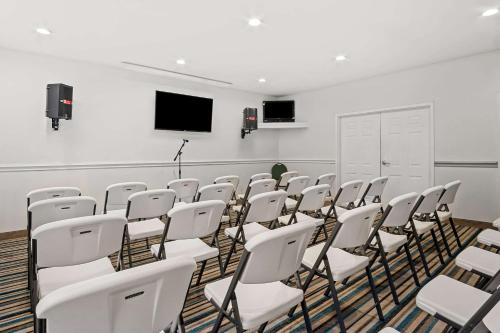 a conference room with white chairs and a flat screen tv at MainStay Suites Addison-Dallas in Addison