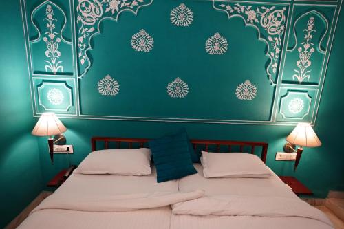 two beds in a room with a green wall at Haveli Kalwara - A Heritage Hotel in Jaipur