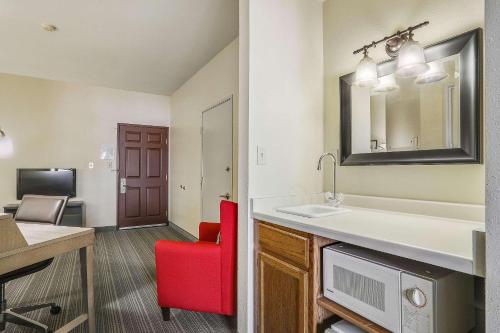 a bathroom with a sink and a red chair at Country Inn & Suites by Radisson, Green Bay, WI in Ashwaubenon