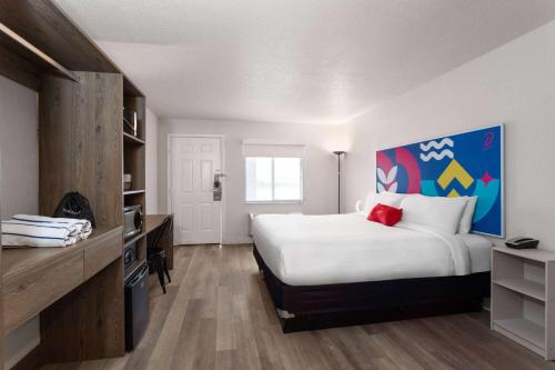 a bedroom with a large white bed with a painting on the wall at Howard Johnson by Wyndham Orlando Lake Buena Vista South in Kissimmee
