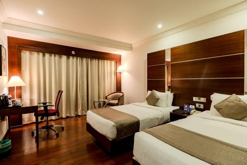 a hotel room with two beds and a desk at Olive Downtown in Cochin